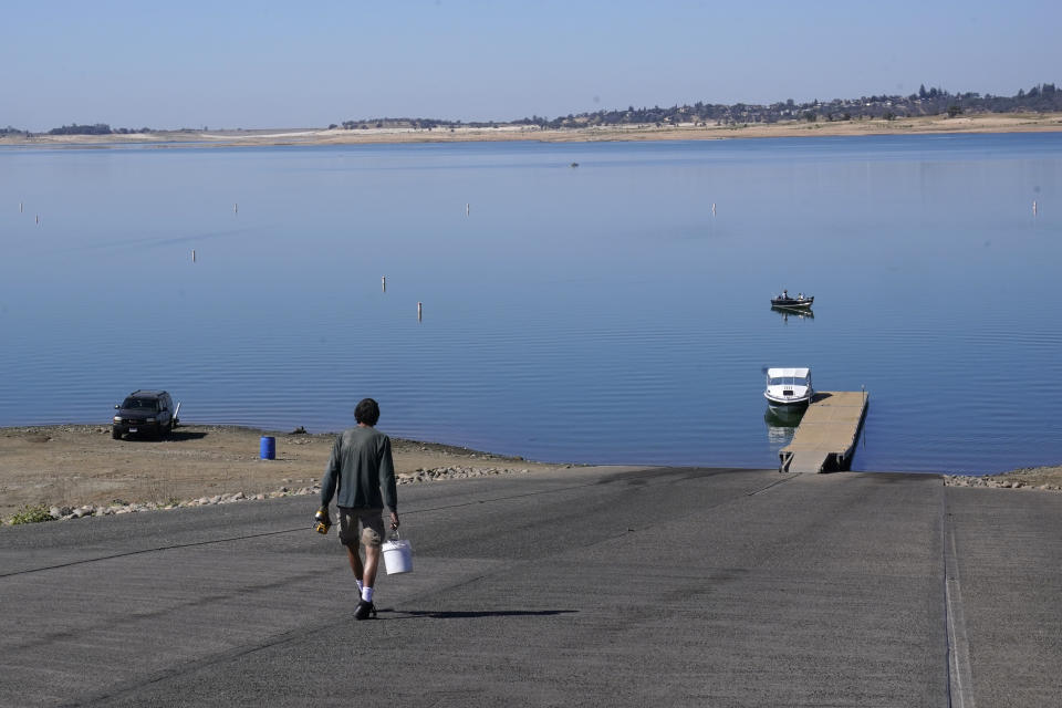 A man makes the long walk down the Folsom Lake boat ramp that is normally underwater in Folsom, Calif., Monday, Oct. 3, 2022. The reservoir is filled to about 70% of its historical average as California began its new water year that started Oct. 1. The past three years have been California's driest on record and state officials said Monday that they're preparing for the streak to continue. (AP Photo/Rich Pedroncelli)