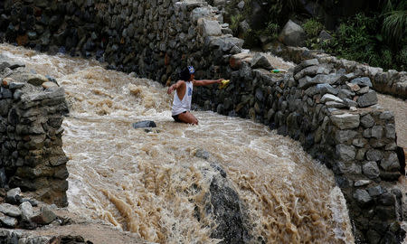 A local miner wades through water as he walks down from a mountain in Benguet a day after Typhoon Haima struck northern Philippines. REUTERS/Erik De Castro