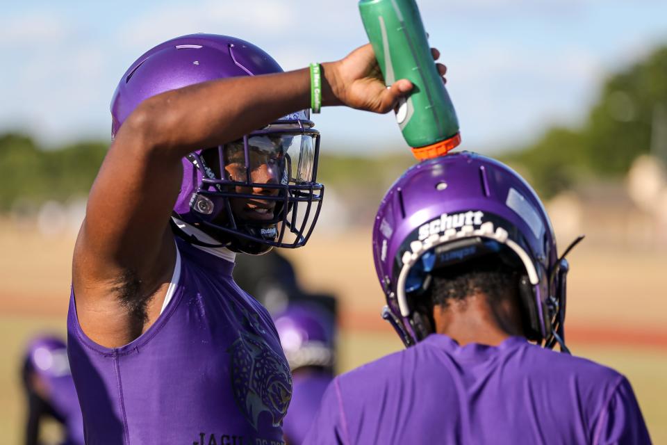 LBJ running back Sedrick Alexander pours water on a teammate's head during the team's practice on Aug. 1. Football coaches are encouraging their players to hydrate before and after practice to combat the Texas heat.