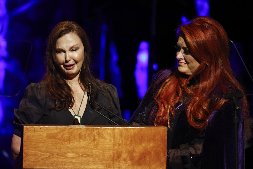 Ashley Judd, a la izquierda, llora junto a su hermana Wynonna Judd al hablar en la ceremonia de incorporación al Salón de la Fama de la Música Country, el domingo 1 de mayo de 2022 en Nashville, Tennessee. La ceremonia fue al día siguiente de que su madre, la legendaria cantante country Naomi Judd, falleciera. (Foto por Wade Payne/Invision/AP)