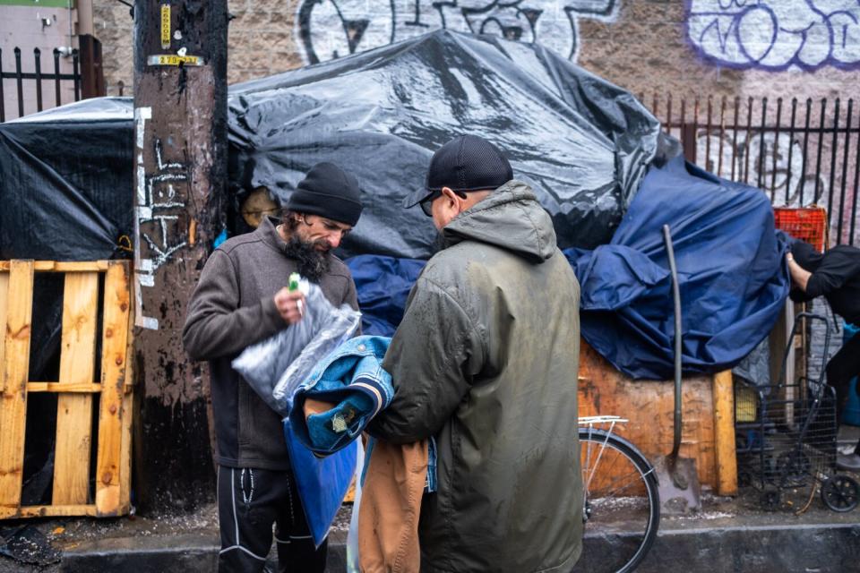 Hengel Bonilla, a volunteer with Pauly's Project, hands Javier Contreras a jacket.