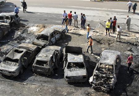 People stand at the site of a car bomb attack in Baghdad's al-Shaab district, October 27, 2013. REUTERS/Thaier Al-Sudani