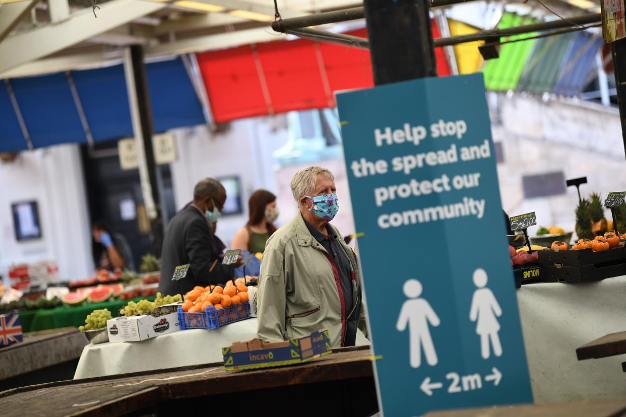 People wearing face masks as a precaution against the transmission of the novel coronavirus shop at an open fruit and vegetable market in Leicester, central England on July 17, 2020, as local lockdown restrictions remain in force due to a spike in cases of the novel coronavirus in the city. - Boris Johnson said on July 17 he hoped Britain would "return to normality" by November despite being badly affected by the coronavirus and predictions of a second wave of cases during winter months. The prime minister announced fresh powers for councils to impose  local lockdowns, such as one currently in place in the English midlands city of Leicester, if there were increased number of cases elsewhere. The government on July 16 annouced a partially ease a two-week-old local lockdown in Leicester, after the number of new coronavirus cases had fallen, but remained well above the average for England which means restrictions on schools, early years childcare and non-essential retail stores will be relaxed from July 24, but that other measures impacting travel, social gatherings and the hospitality sector would remain. (Photo by DANIEL LEAL-OLIVAS / AFP) (Photo by DANIEL LEAL-OLIVAS/AFP via Getty Images)