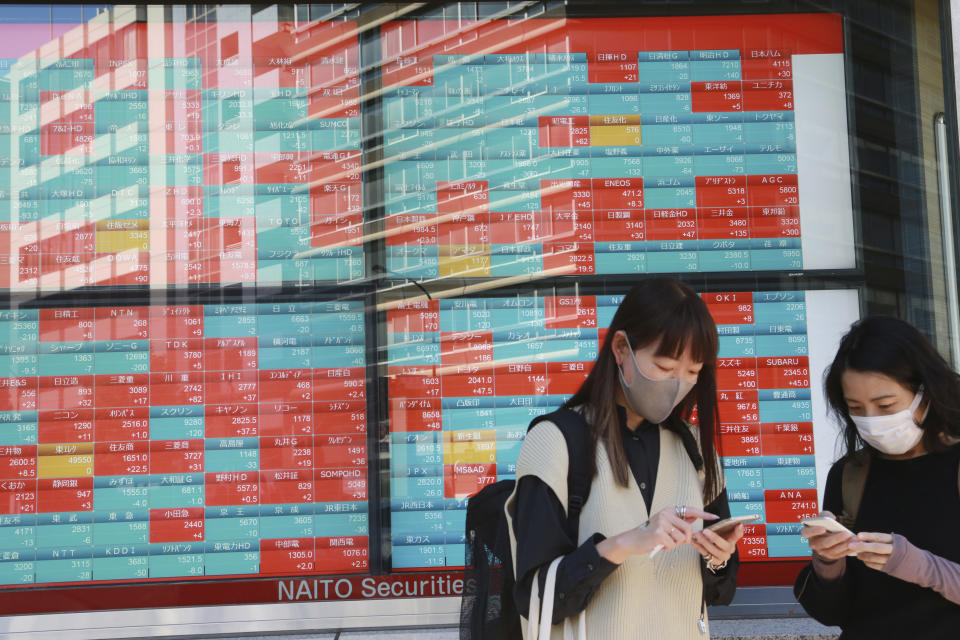 People stand by an electronic stock board of a securities firm in Tokyo, Monday, Oct. 18, 2021. Asian shares were mostly lower on Monday after China reported its economy grew at a meager 4.9% annual pace in July-September. (AP Photo/Koji Sasahara)