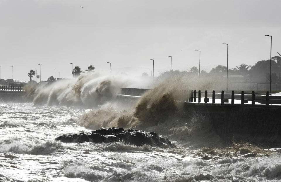 Waves break over Sea Point's promenade in Cape Town, South Africa, Monday, July 8, 2024. City authorities say nearly 1,000 homes in informal settlements around the city have been destroyed by gale-force winds, displacing around 4,000 people with multiple cold fronts expected until at least Friday. (AP Photo/Nardus Engelbrecht)