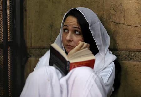 Aya Hijazi, founder of a non-governmental organisation that looks after street children, sits reading a book inside a holding cell as she faces trial on charges of human trafficking, sexual exploitation of minors, and using children in protests, at a courthouse in Cairo, Egypt March 23, 2017. REUTERS/Mohamed Abd El Ghany