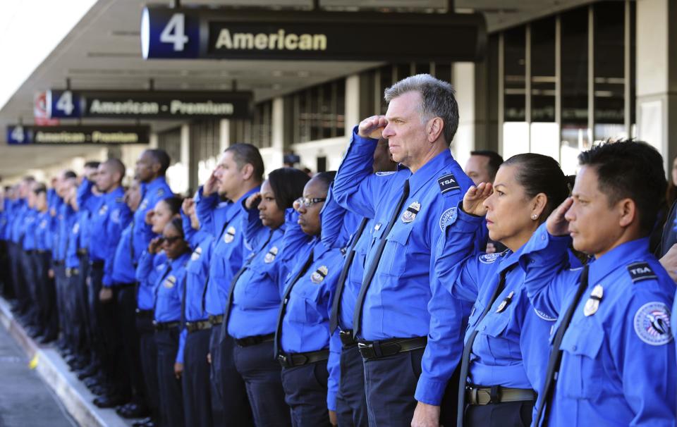 A line of TSA personnel salute the U.S. Honor Flag procession as it leaves Los Angeles International Airport