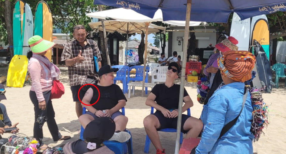 Tourists getting henna tattoo on Bali beach. 