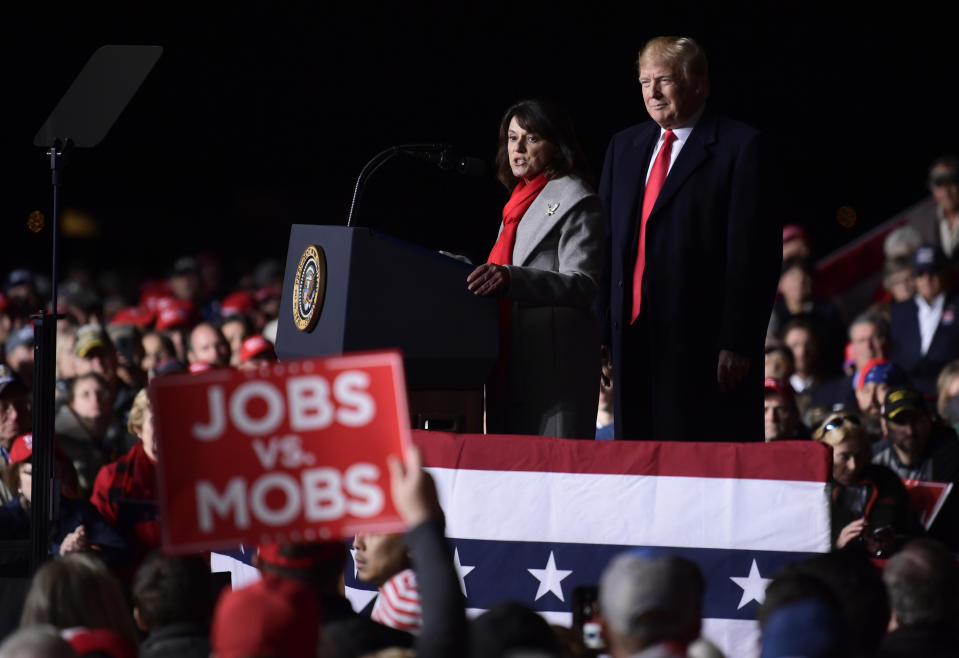 President Donald Trump, right, listens as Republican Senate candidate Leah Vukmir, left, speaks during a rally at Central Wisconsin Airport in Mosinee, Wis., Wednesday, Oct. 24, 2018. (AP Photo/Susan Walsh)