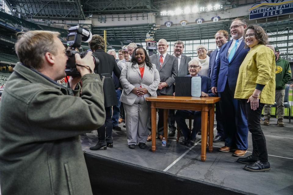 Photographer Joe Koshollek takes a picture of Wisconsin Gov. Tony Evers after Ecvers signed Assembly Bill 438 and Assembly Bill 439 at American Family Field Tuesday, Dec. 5, 2023, in Milwaukee. The bills use public funds to help the Milwaukee Brewers repair their stadium over the next three decades. (AP Photo/Morry Gash)