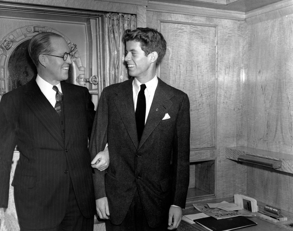 REMOVES ERRONEOUS REFERENCE TO IMMIGRANT - FILE - In this Jan. 5, 1938 file photo, Joseph P. Kennedy, left, U.S. Ambassador to Great Britain, stands with his son, John F. Kennedy, in New York. Kennedy, born in 1917, was the second son, and one of nine children, of business tycoon Joseph P. Kennedy. When first son Joseph Jr. was killed during World War II, Jack became the designated heir. Himself a Navy veteran and survivor of a collision with a Japanese destroyer, he would write to his friend Paul Fay that, once the war was over, "I'll be back here with Dad trying to parlay a lost PT boat and a bad back into a political advantage." (AP Photo)