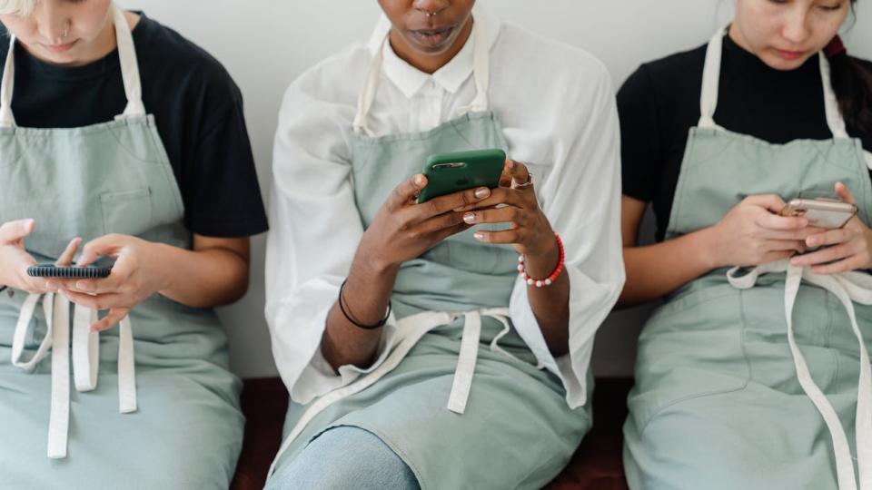 Crop focused multiethnic baristas using smartphones