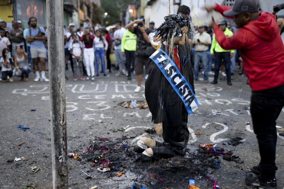 Un residente arroja gasolina sobre una efigie con una banda con la palabra fascista, como parte de la tradicional Quema de Judas del Domingo de Resurrección, en Caracas, Venezuela, el 31 de marzo de 2024. Los venezolanos salen a la calle para presenciar la quema de efigies de Judas, el apóstol que según la tradición traicionó a Jesucristo, pero también representaciones de personalidades que representan el mal y la corrupción. (AP Foto/Ariana Cubillos)