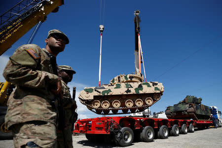 U.S. servicemen walk past, while Bradley infantry fighting vehicles are unloaded for the joint U.S.-Georgian exercise Noble Partner 2016 in Vaziani, Georgia, May 5, 2016. REUTERS/David Mdzinarishvili