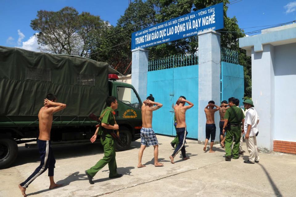 This picture taken on 9 November 2016 shows recaptured inmates, who escaped from a drug rehabilitation centre, being escorted by police back to their rehab centre in the in the southern province of Ba Ria-Vung Tau following a mass breakout (AFP via Getty Images)