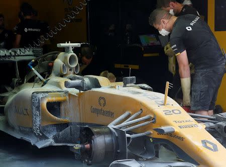 Formula One - F1 - Malaysia Grand Prix - Sepang, Malaysia - 30/9/16 Crew members work on the damaged car of Renault's Kevin Magnussen of Denmark after it caught fire in the first practice. REUTERS/Edgar Su