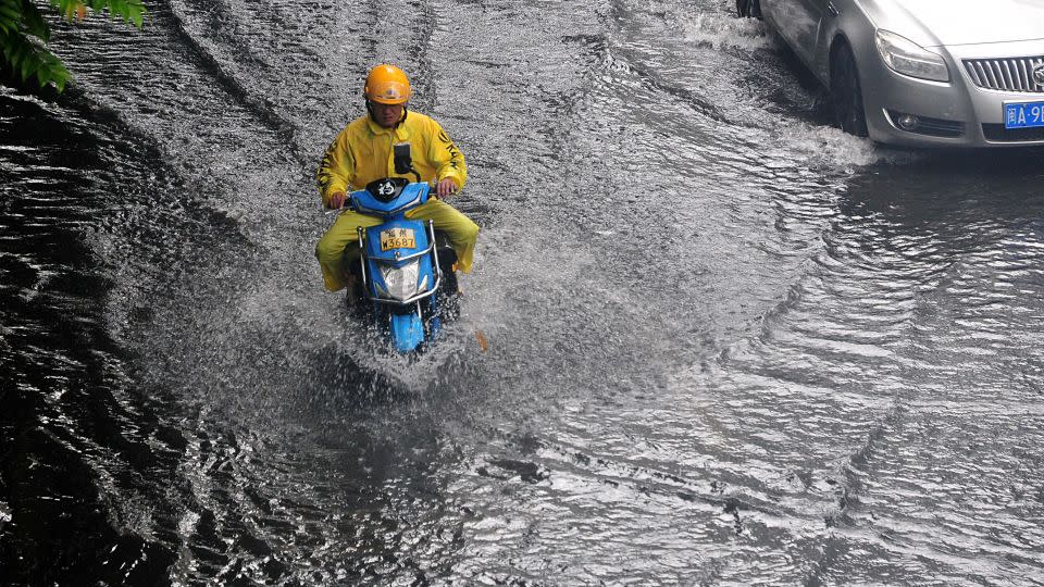 A commuter navigates a waterlogged road after heavy rain in Fuzhou, in China's Fujian province, on June 16. - Zhang Bin/China News Service/VCG/Getty Images