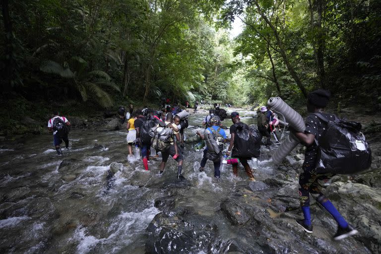 Migrantes cruzan el río Acandi en su viaje hacia el norte, desde Colombia a Panamá con la esperanza de llegar a Estados Unidos