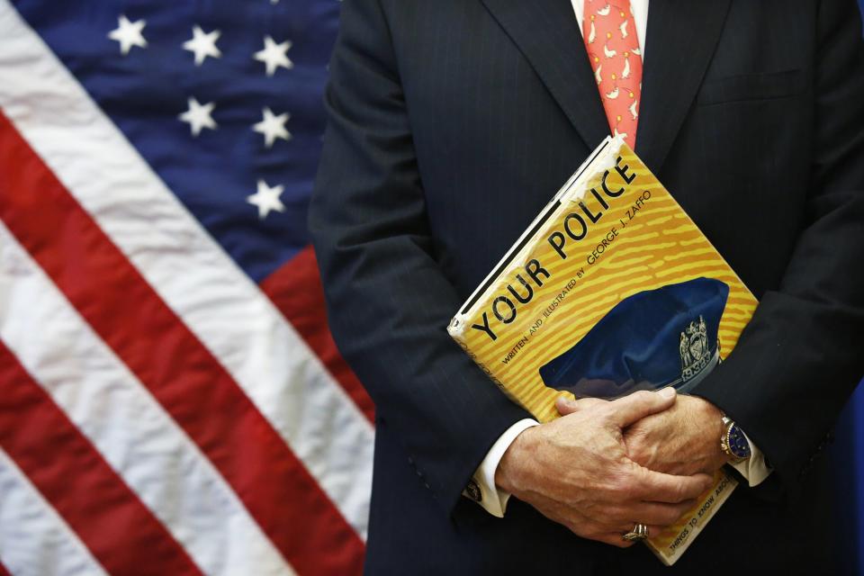 Bratton holds a book as he attends a news conference in Brooklyn