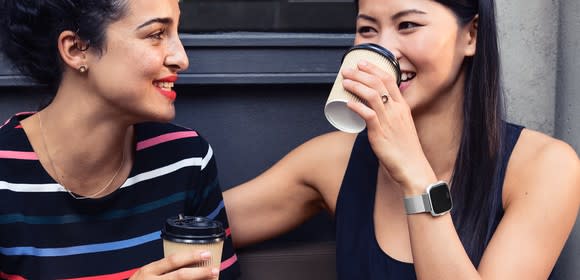 Two smiling women with one wearing a Versa smartwatch