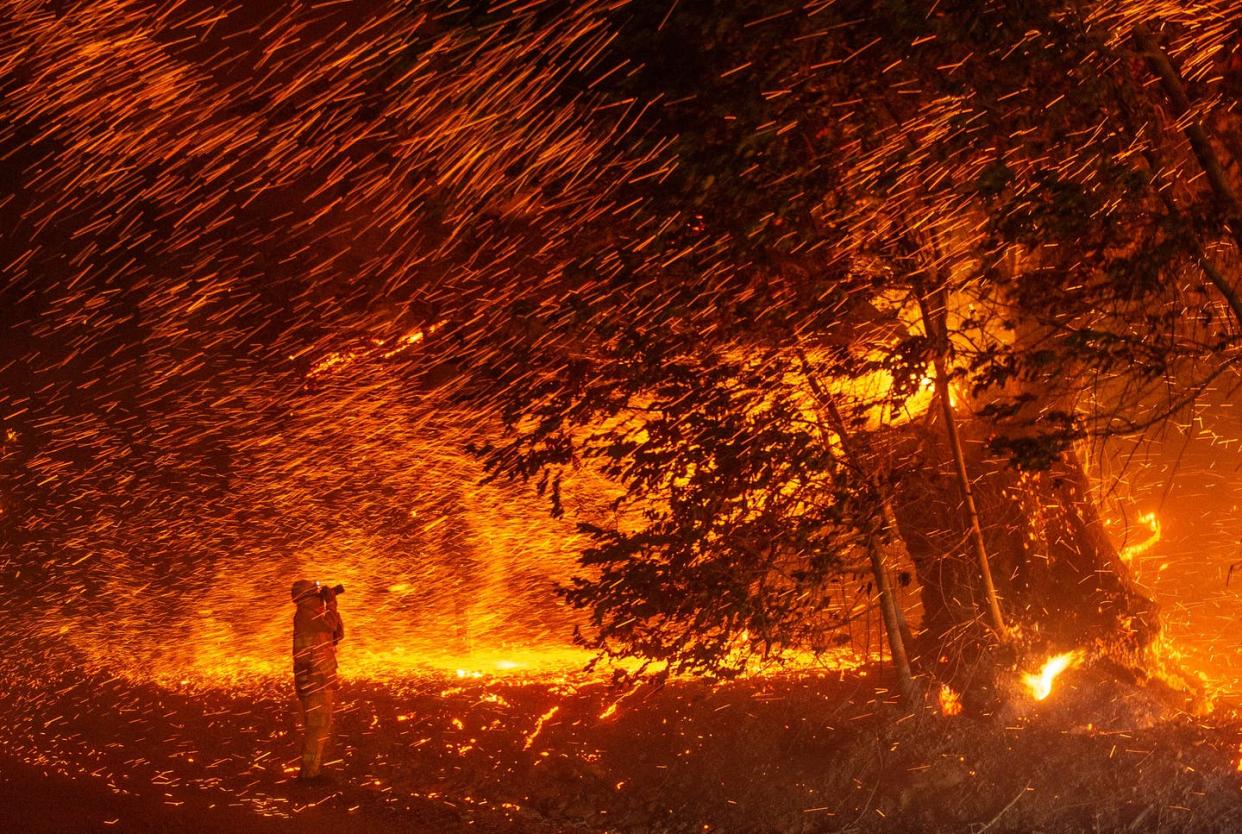 <span class="caption">A photographer stands in a rain of flaming embers during a fire in California in 2019.</span> <span class="attribution"><a class="link " href="https://www.gettyimages.com/detail/news-photo/photographer-takes-photos-amidst-a-shower-of-embers-as-wind-news-photo/1177959030" rel="nofollow noopener" target="_blank" data-ylk="slk:Josh Edelson/AFP via Getty Images;elm:context_link;itc:0;sec:content-canvas">Josh Edelson/AFP via Getty Images</a></span>