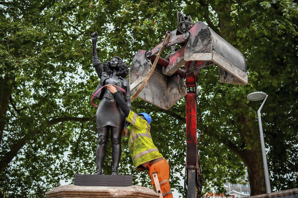 A contractor uses ropes to secure the statue "A Surge of Power (Jen Reid) 2020" by artist Marc Quinn, which had been installed on the site of the fallen statue of the slave trader Edward Colston, as they prepare to remove and load it into a recycling and skip hire lorry, in Bristol, Thursday, July 16, 2020. The sculpture of protestor Jen Reid was installed without the knowledge or consent of Bristol City Council and was removed by the council 24 hours later. (Ben Birchall/PA via AP)