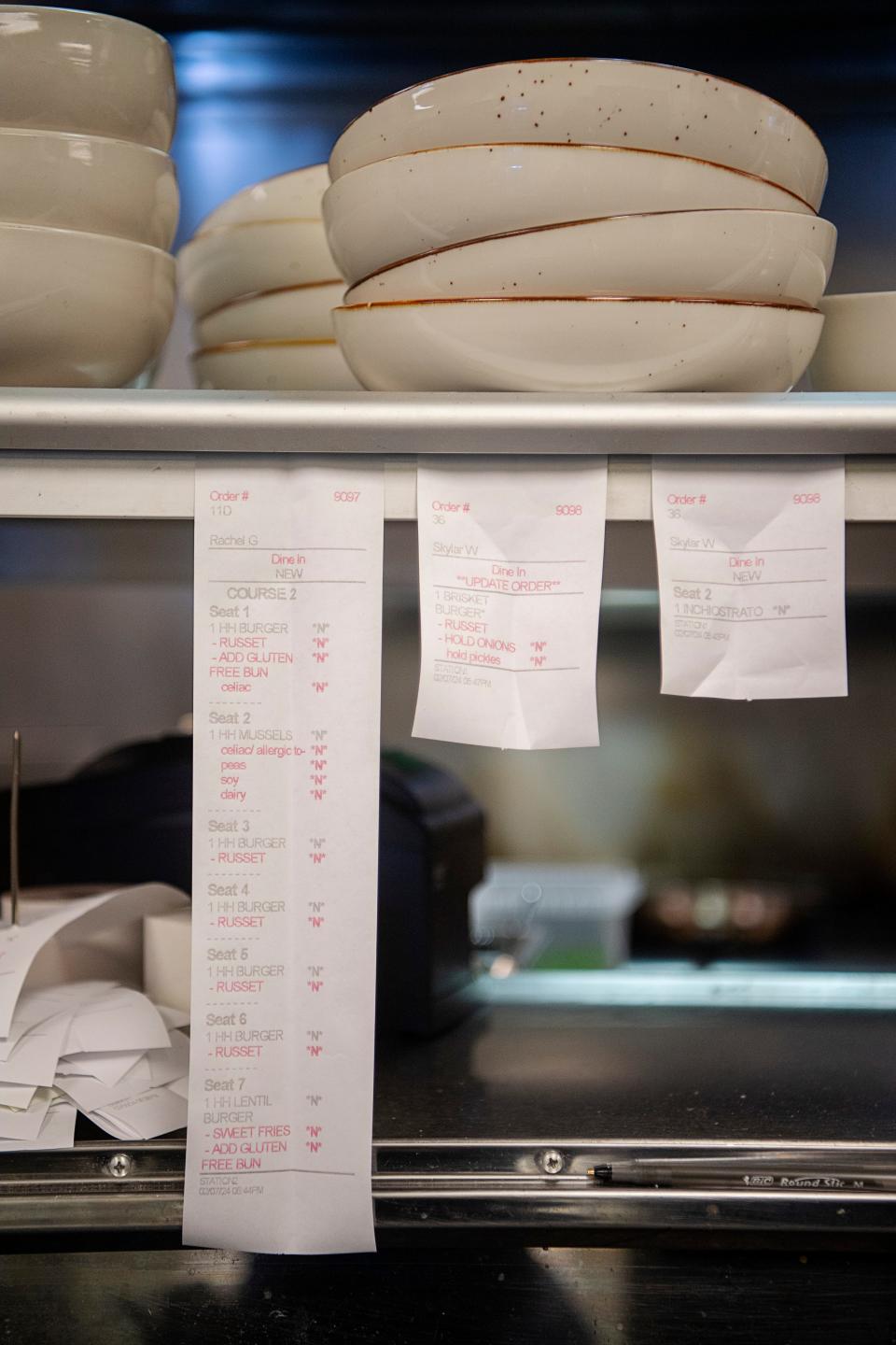 Food order tickets hang in a restaurant kitchen in Asheville.