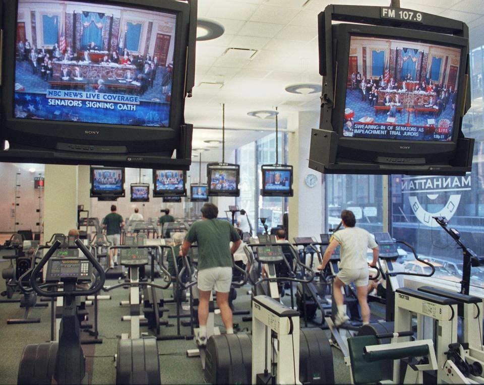 A group of people exercise 07 January at the Manhattan Athletic Club in New York as they watch a live television broadcast of the impeachment trial of US President Bill Clinton. US Supreme Court Justice William Rehnquist will preside over the trial