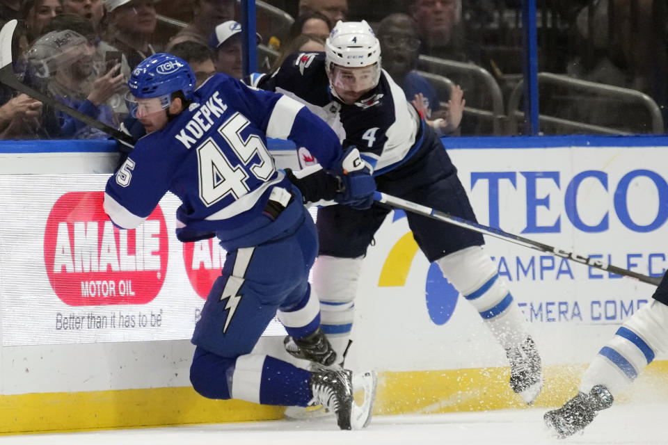 Winnipeg Jets defenseman Neal Pionk (4) knocks down Tampa Bay Lightning left wing Cole Koepke (45) during the first period of an NHL hockey game Wednesday, Nov. 22, 2023, in Tampa, Fla. (AP Photo/Chris O'Meara)