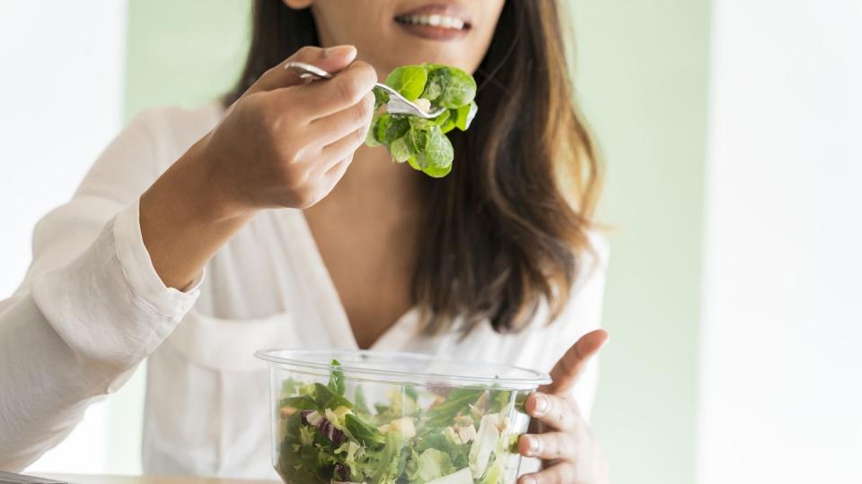 crop view of young architect eating mixed salad at desk