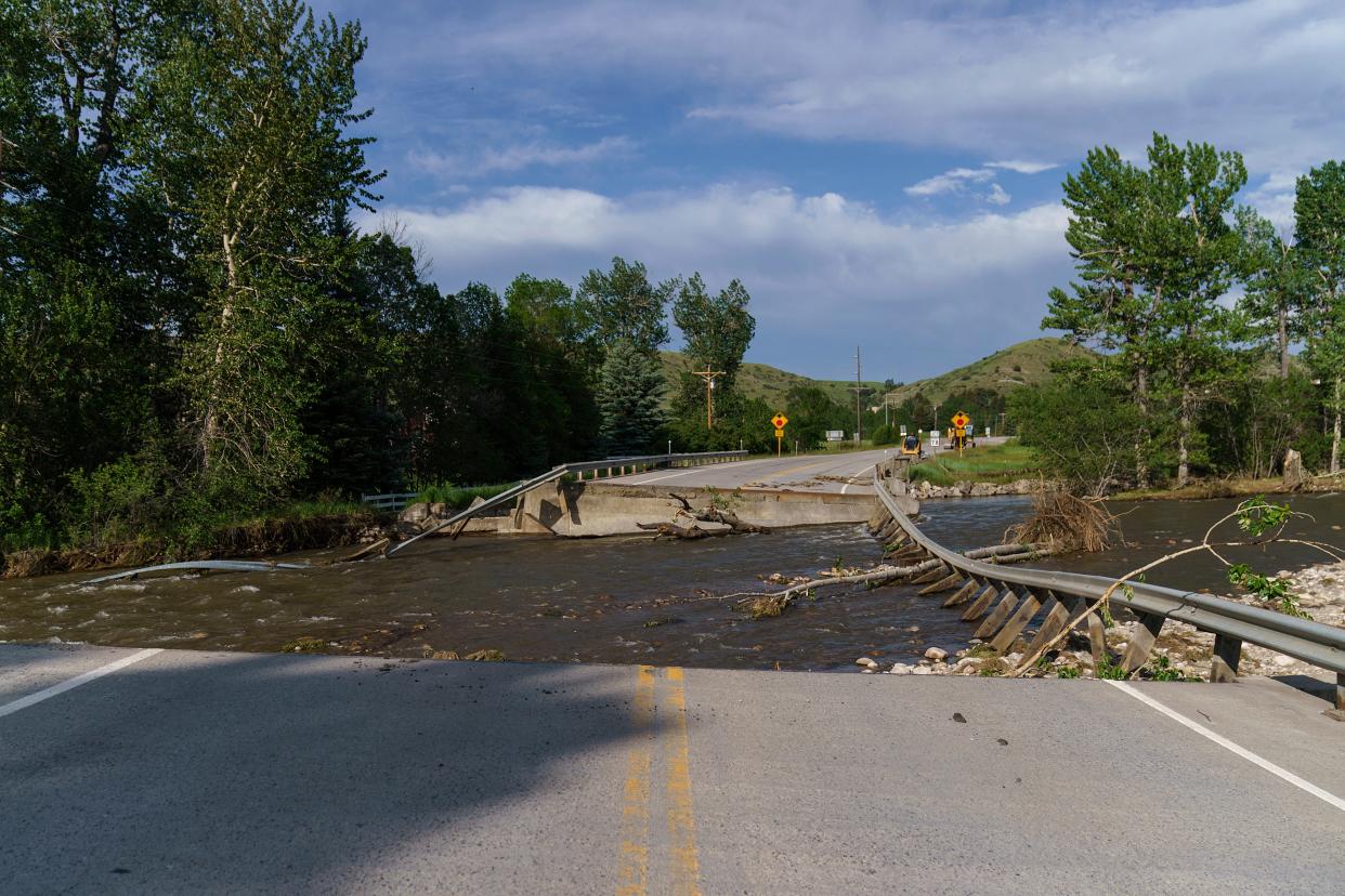 A river flows through a missing section of a key bridge that leads to the tourist town of Fishtail, Mont., on Friday.