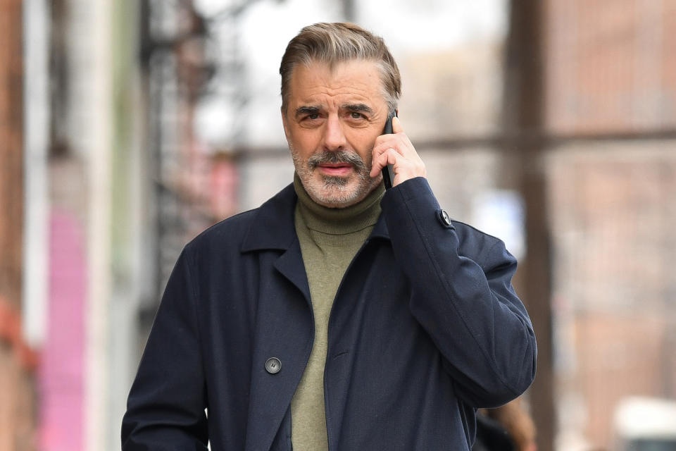 Noth talks into a phone as he stands outside