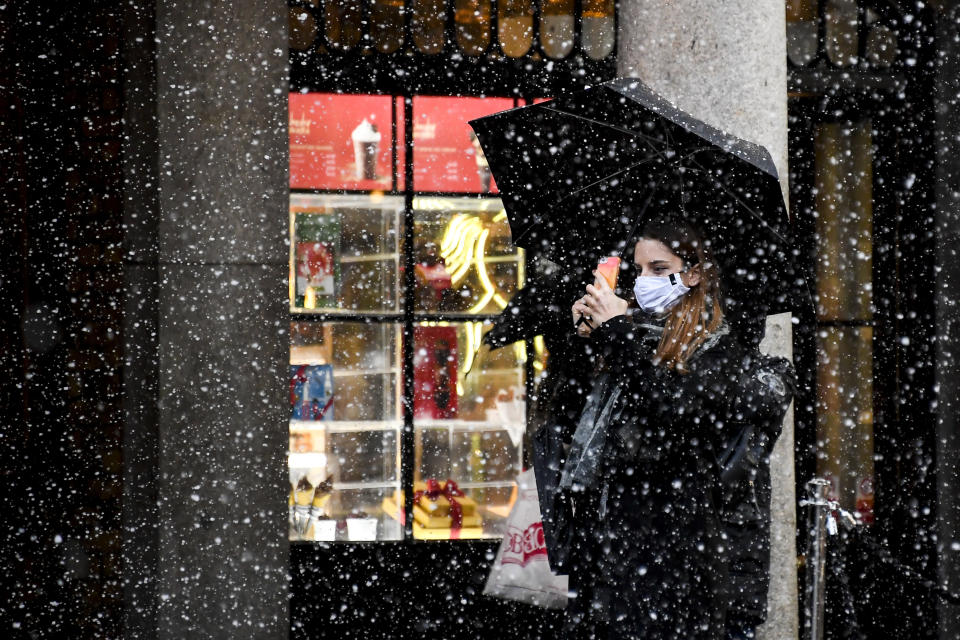 A woman wearing a face mask takes a photo on her phone in Covent Garden, London, Thursday, Dec. 3, 2020. Britain became the first country in the world to authorize a rigorously tested COVID-19 vaccine Wednesday and could be dispensing shots within days — a historic step toward eventually ending the outbreak that has killed more than 1.4 million people around the globe. (AP Photo/Alberto Pezzali)