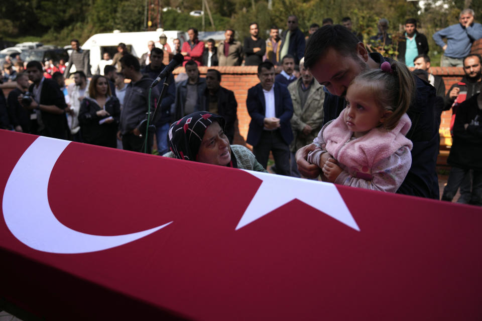 Elmas Ayvaz, 58, and Asel Meva, 3, aunt and daughter of the miner killed in a coal mine explosion Selcuk Ayvaz, 33, mourn over his coffin during his funeral outside a mosque in Amasra, in the Black Sea coastal province of Bartin, Turkey, Saturday, Oct. 15, 2022. (AP Photo/Khalil Hamra)