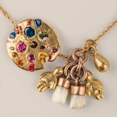 Charm necklace with spinning disc, teeth and gold figures