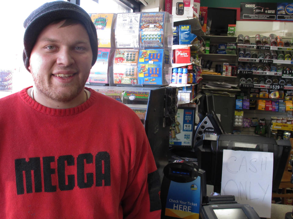 John Scaduto stands next to a Powerball lottery machine on Monday, Nov. 26, 2012, in Long Beach, N.Y. Scaduto said  he lost his job as a sous chef when the restaurant he works at was flooded in Superstorm Sandy. He said  he has already bought more than $100 worth of Powerball tickets in advance of Wednesday's drawing and would open his own restaurant if he has the winning numbers. (AP Photo/Frank Eltman)