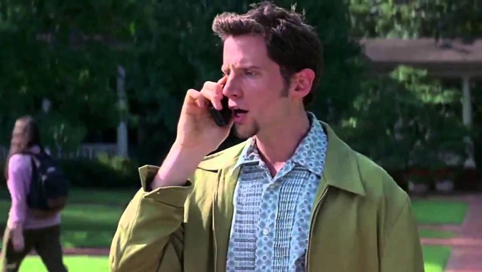 Jamie Kennedy as Randy Meeks in Scream stands outside wearing green jacket talking on cell phone