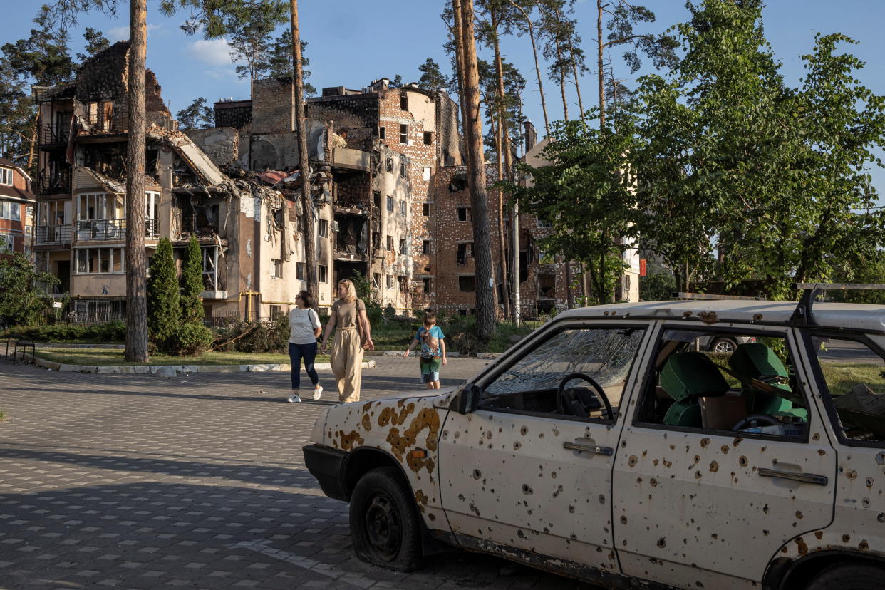 People walk by destroyed buildings in Irpin, outside Kyiv, as Russia's attacks on Ukraine continues, June 9, 2022. REUTERS/Marko Djurica