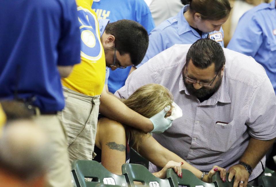 FILE - In this July 6, 2015, file photo, a fan is helped after being hit by a foul ball during the ninth inning of a baseball game between the Milwaukee Brewers and the Atlanta Braves in Milwaukee. Illinois' two senators have urged Major League Baseball to be more transparent about fans who are injured by foul balls, saying the lack of data is creating confusion about the extent of the problem. Democratic Sens. Dick Durbin and Tammy Duckworth said in a letter to baseball Commissioner Rob Manfred this week that MLB should "collect and report data about fan injuries." (AP Photo/Morry Gash, File)