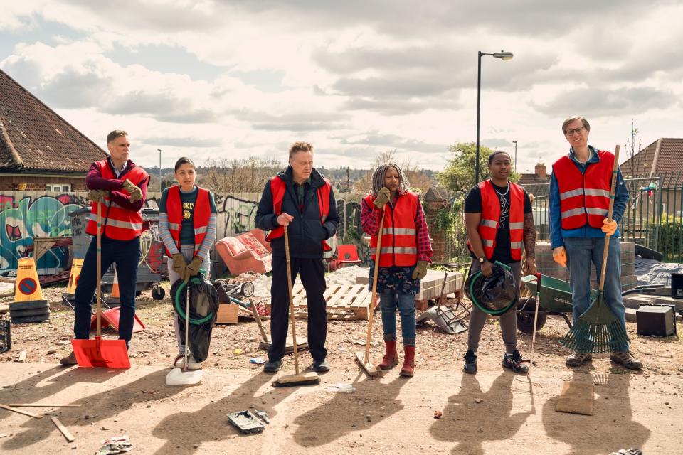 A line of people in work jackets and carrying various cleaning equipment