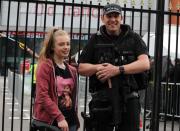 <p>Emma Prigg, 14, from Stoke-on-Trent, stands next to an armed police officer before the One Love Manchester benefit concert (PA) </p>