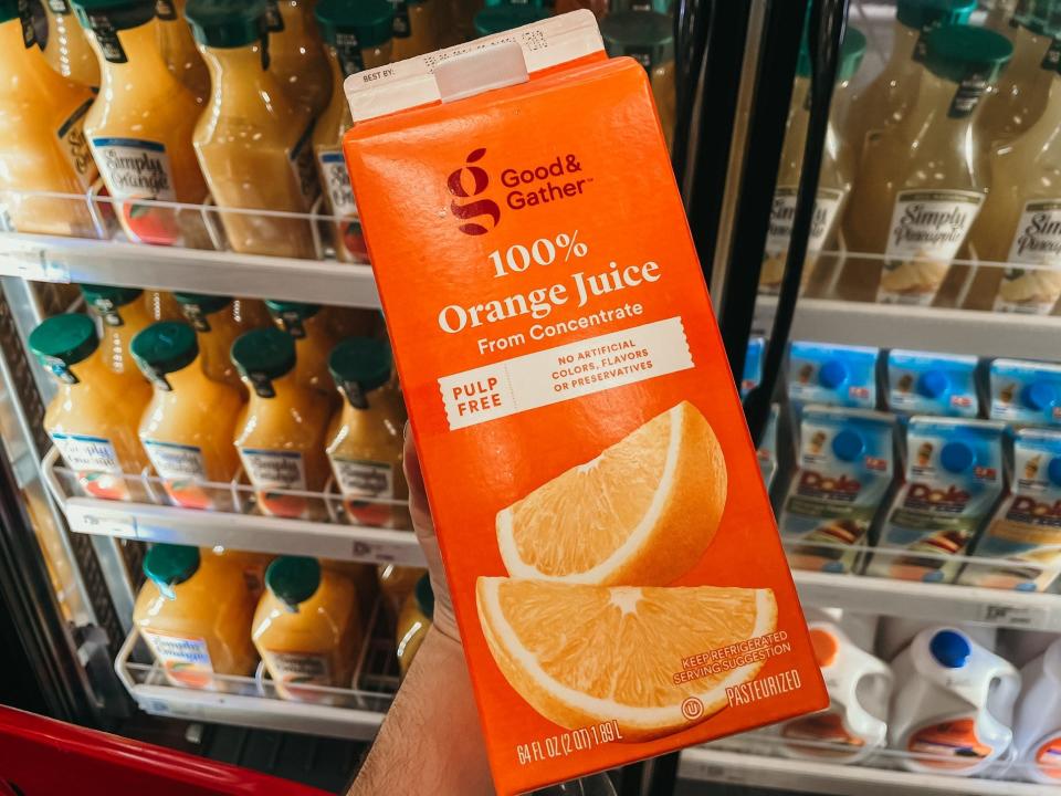 hand holding up a carton of generic target orange juice