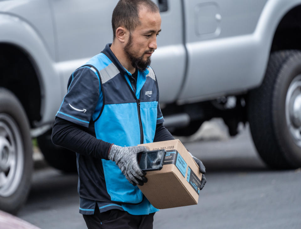 Berks County, Pennsylvania, USA, April 26, 2020-Amazon.com delivery person wearing gloves packages on suburban street