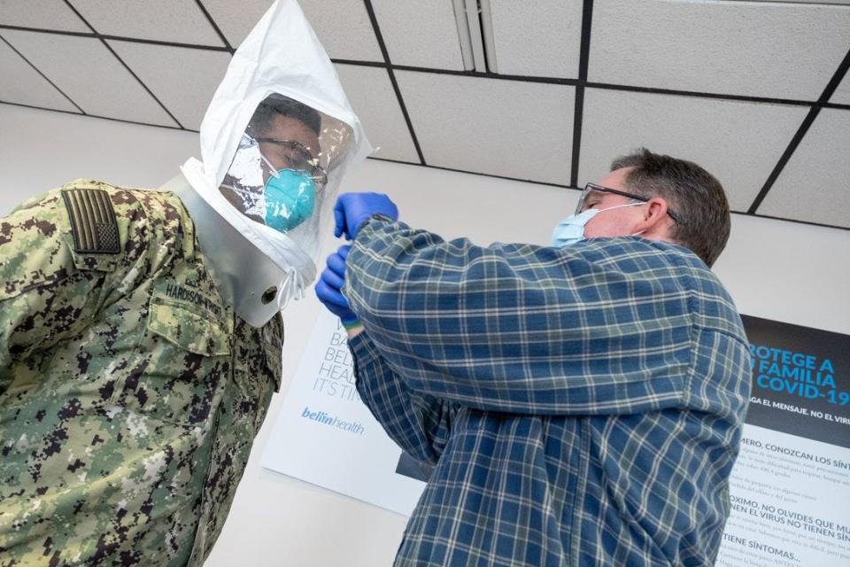 A Bellin Health staff member fits a U.S. Navy member with personal protective equipment as the military prepared to start a 30-day relief deployment at the Green Bay hospital.