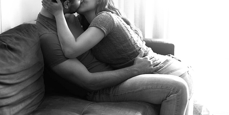 couple kissing on couch wearing jeans