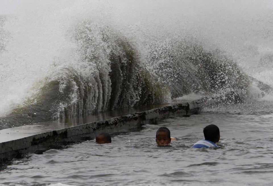 Children swim in a flooded walkway as rough waves crash on concrete banks along the coast of Manila Bay brought by Super Typhoon Usagi in Navotas City, metro Manila September 21, 2013. The year's most powerful typhoon slammed into the Philippines' northernmost islands on Saturday, cutting communication and power lines, triggering landslides and inundating rice fields, officials said. Packing winds of 185 kph (114 mph) near the center and gusts of up to 220 kph, Typhoon Usagi weakened after hitting the Batanes island group, and is moving slowly west-northwest at 19 kph towards southern China, the weather bureau said. REUTERS/Romeo Ranoco (PHILIPPINES - Tags: DISASTER SOCIETY ENVIRONMENT)