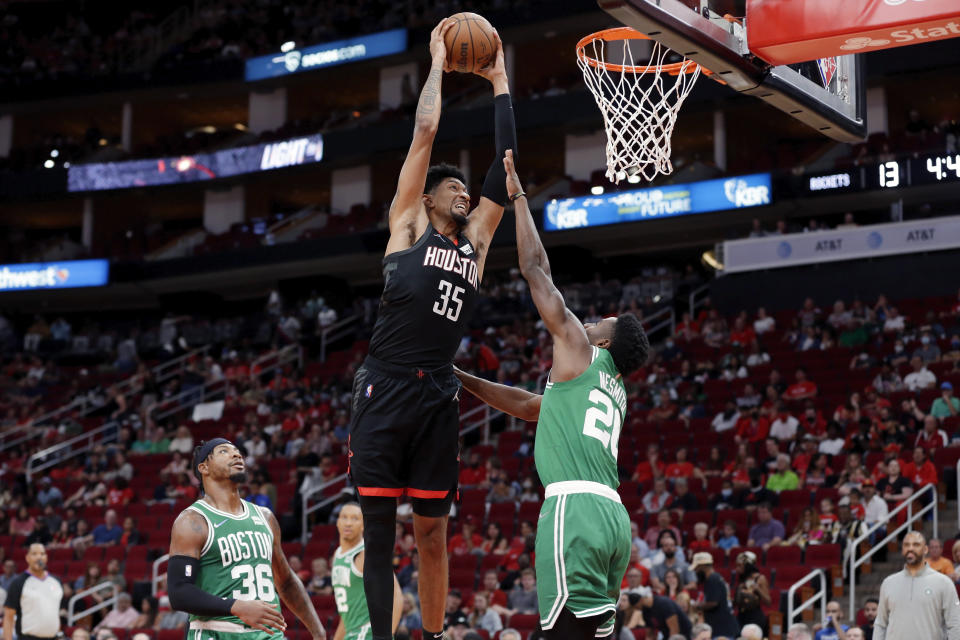 Houston Rockets center Christian Wood (35) dunks over Boston Celtics forward Aaron Nesmith, right, as guard Marcus Smart (36) looks on during the first half of an NBA basketball game Sunday, Oct. 24, 2021, in Houston. (AP Photo/Michael Wyke)