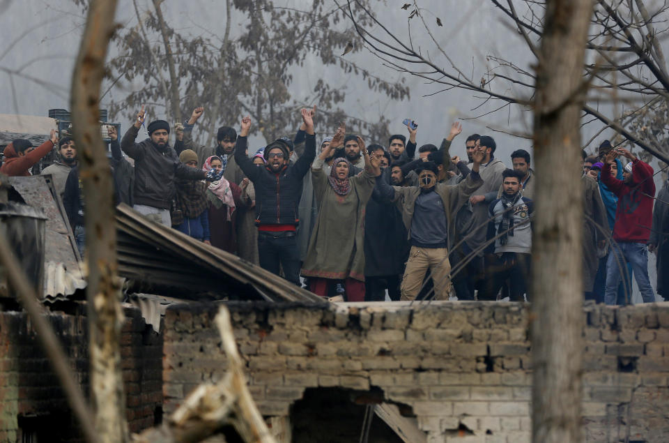 Kashmiri villagers shout pro-freedom slogans next to the residential houses damaged in a gun-battle in Mujagund area some 25 Kilometers (16 miles) from Srinagar, Indian controlled Kashmir, Sunday, Dec. 9, 2018. Indian troops killed three suspected rebels in the outskirts of disputed Kashmir's main city ending nearly 18-hour-long gunbattle, officials said Sunday. (AP Photo/Mukhtar Khan)