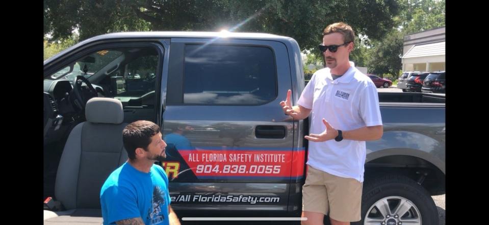 Driving instructor Mike Greiner, right, talks to a student paralyzed from a motocross accident. This lesson started with learning about the driving school's adaptive hand-controlled features