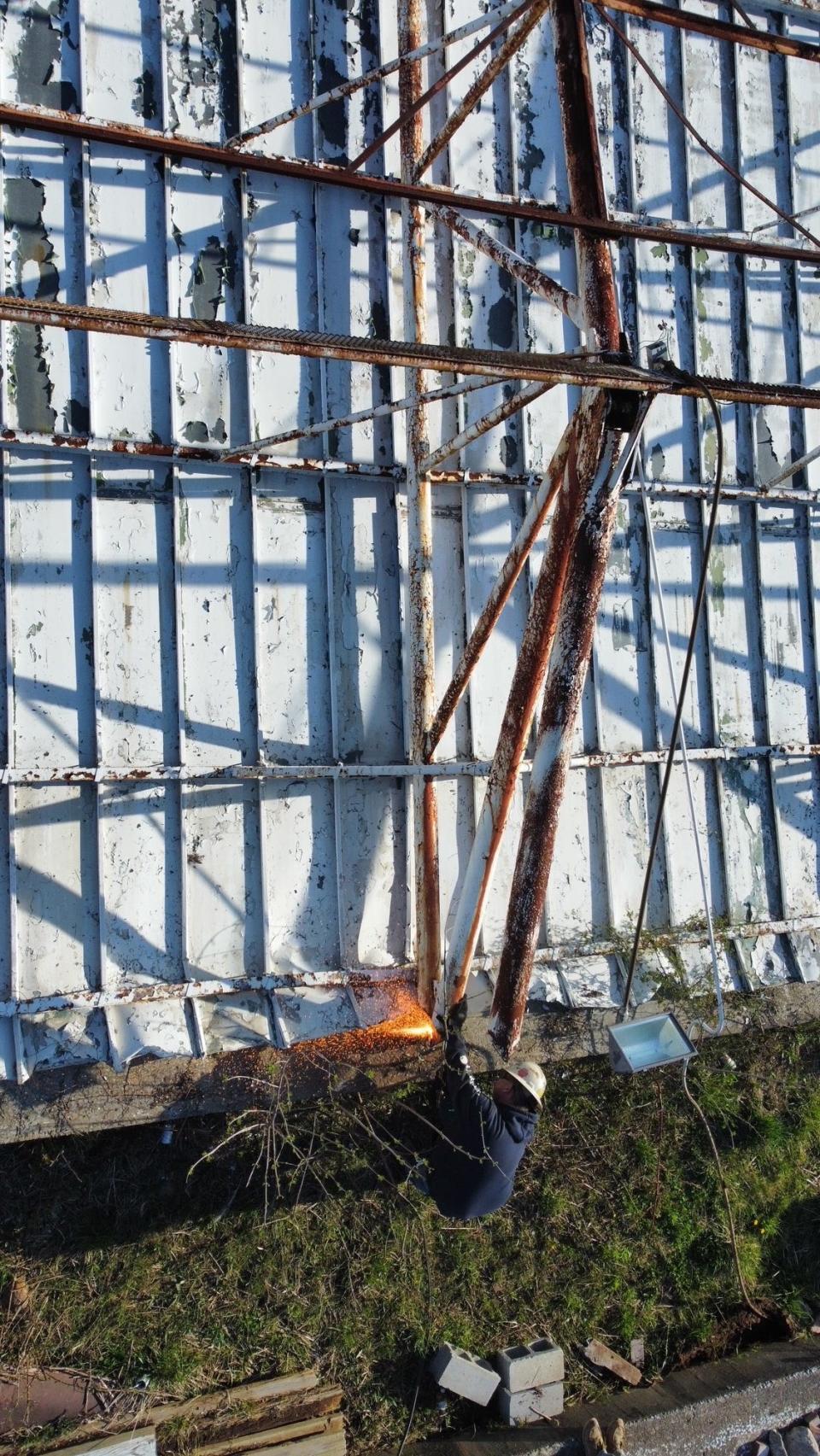 A worker cuts a support bean before the big screen at the former Sunset Drive-In was dropped Tuesday to make way for a new barn at Buckeye Barn Salvage at Ohio 309 and 314.